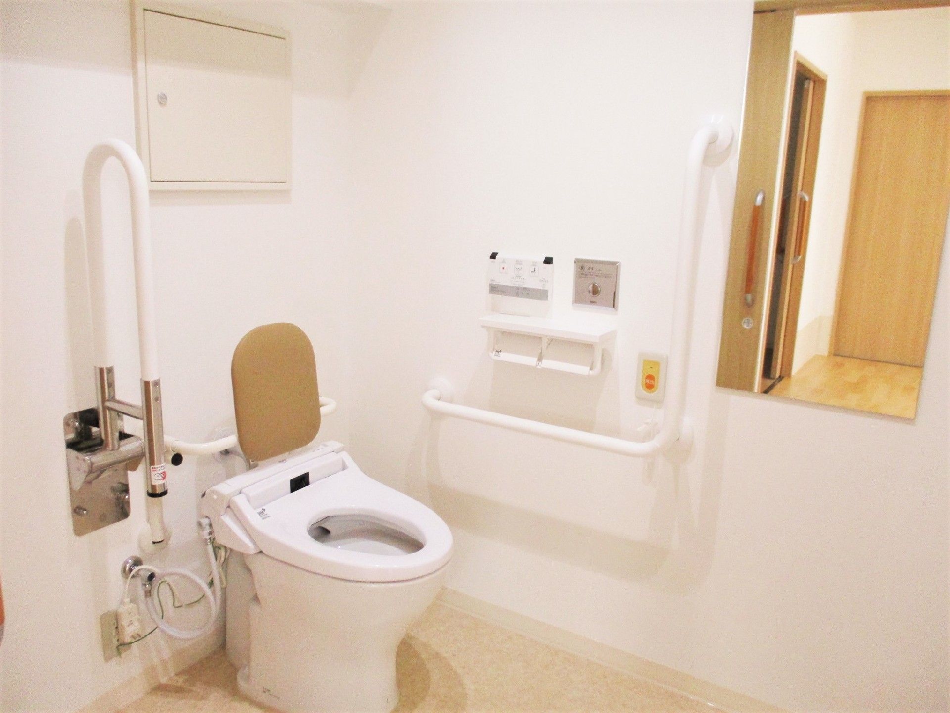 手すりや背もたれ付きのトイレは広く、壁には呼び出しボタンや鏡も設置されている。