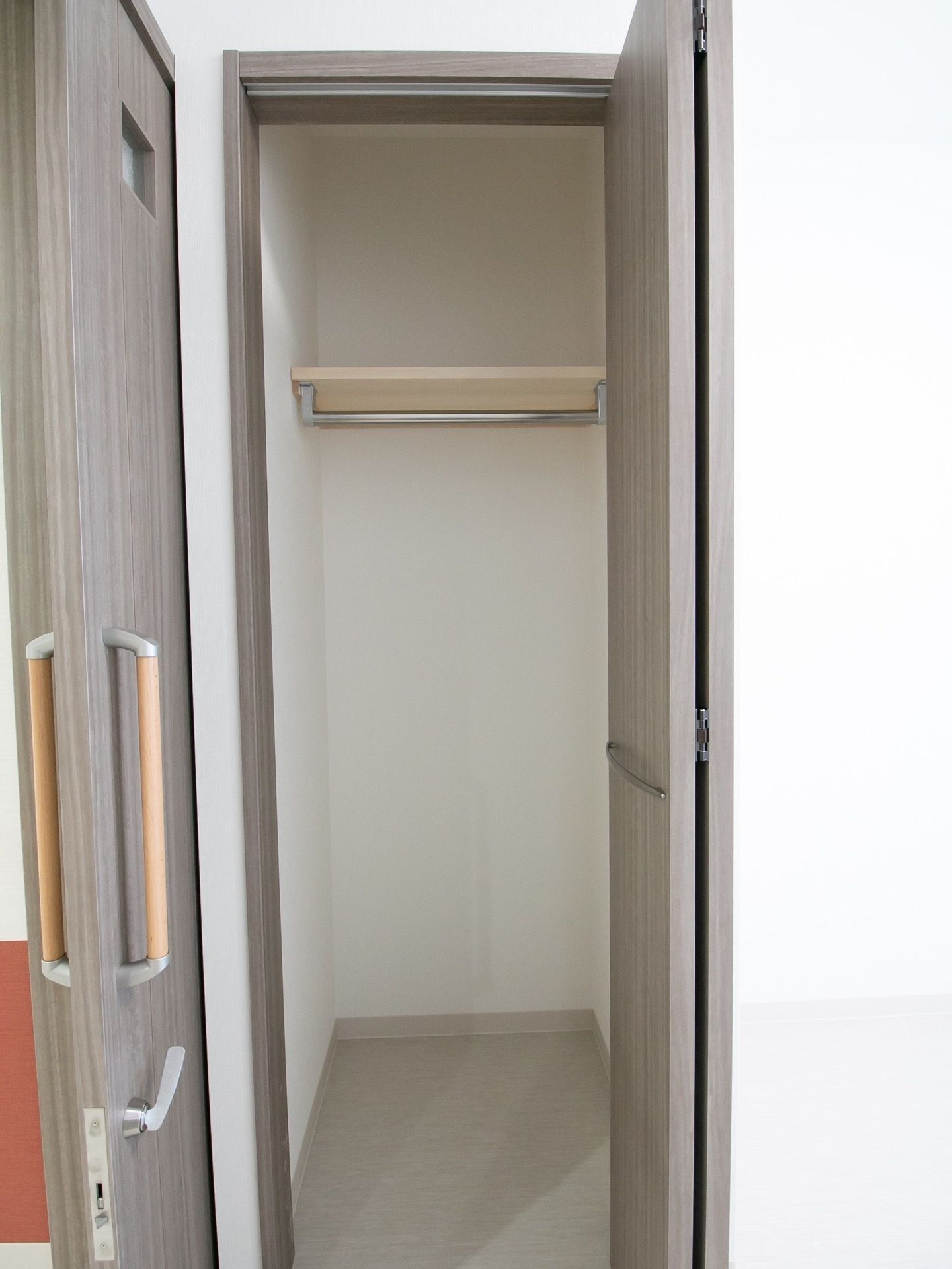 水の入ったコップを持ったエプロンを付けた女性スタッフが薬を飲もうとしている高齢女性のそばで微笑んでいる。