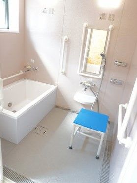 シャワーやシャワーチェアが付いた一人用の浴室。大きな窓があり、壁には手すりも付いている。