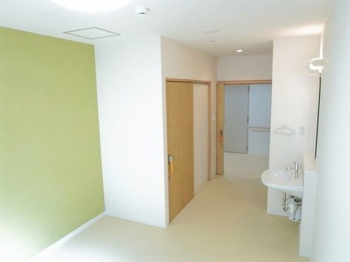 居室には洗面所やトイレが付き、壁の一面がグリーン。出入り口は引き戸となっている。