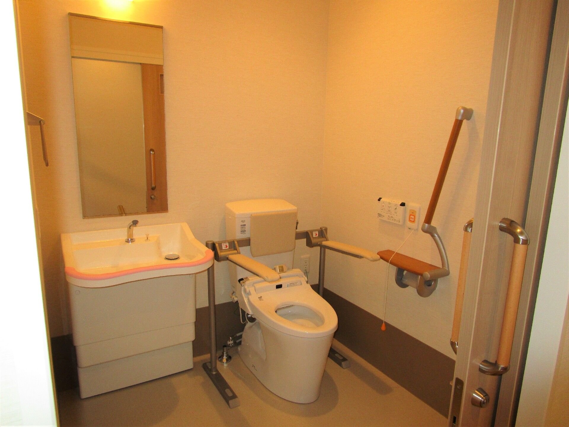 洗面所とトイレがあり、トイレには手すりや背もたれが付き、壁には呼び出しボタンがある。