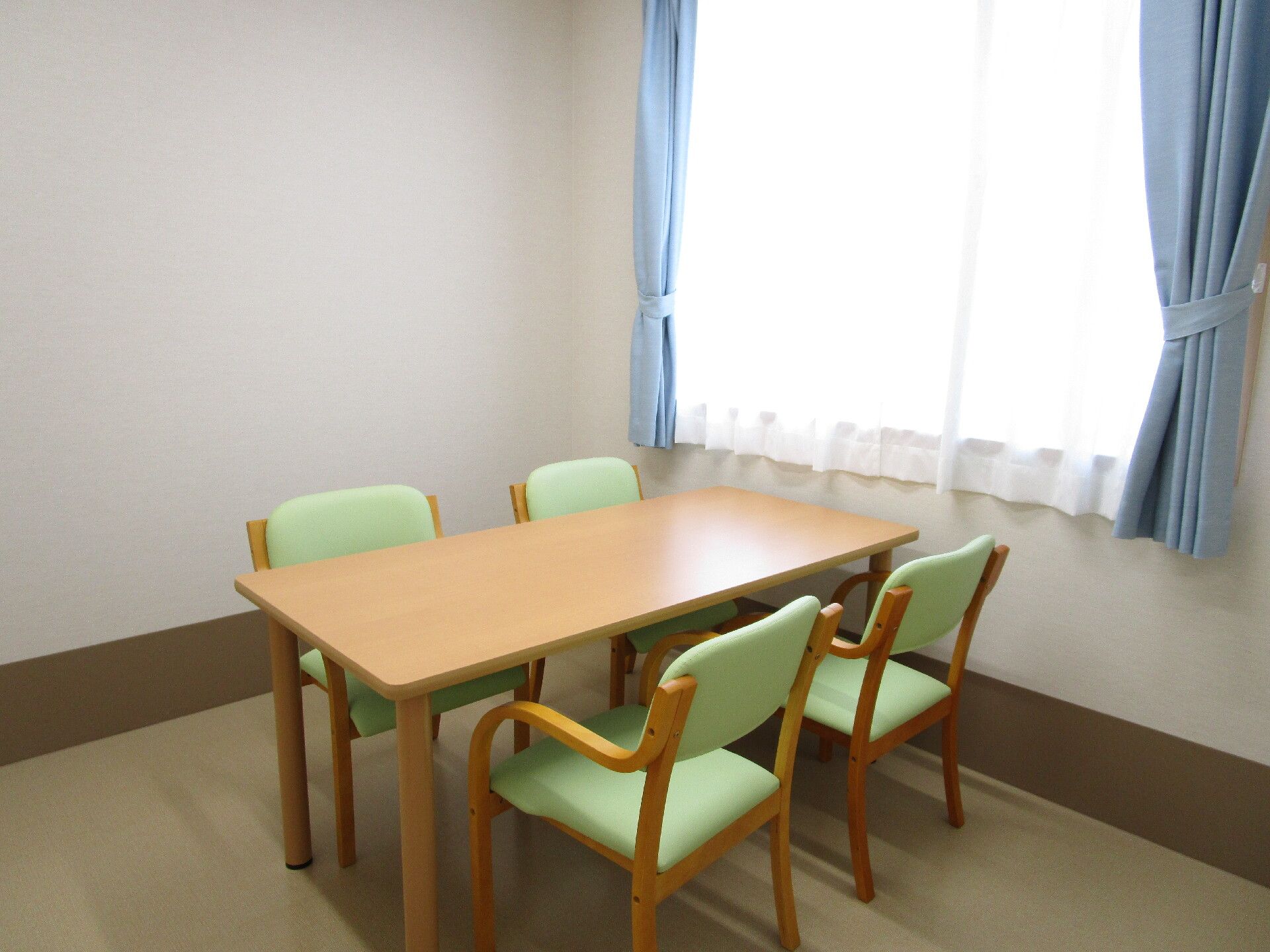 大きな窓にはカーテンが付き、4人掛けのテーブルが置かれている。