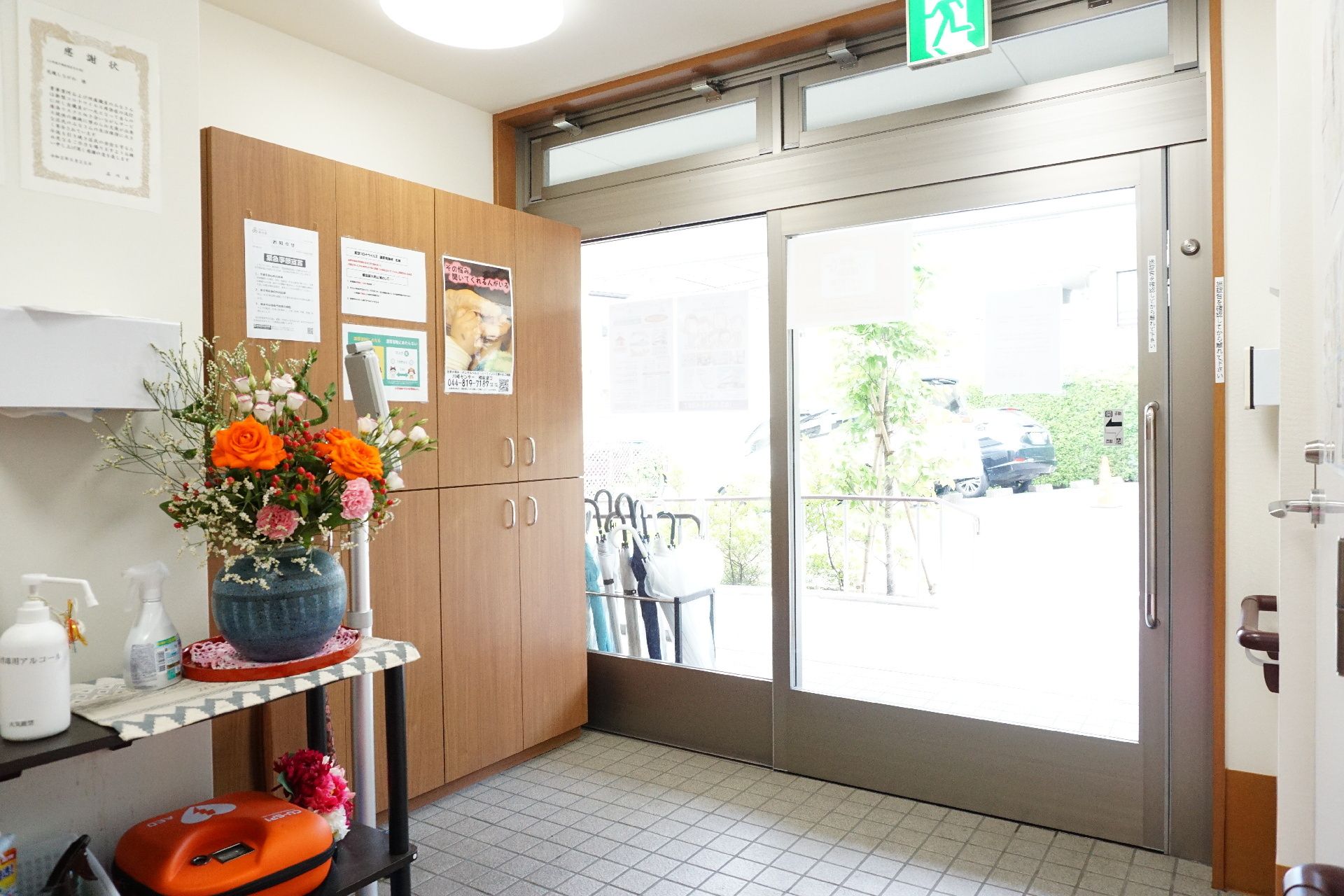 カメラに向かって笑顔を見せる車いすの女性とその家族、男女のスタッフの様子