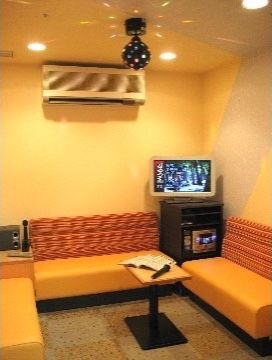 室内には音響調節の設備とディスプレイが置かれ、テーブルを囲んでソファが設けられている。壁にはエアコン、天井にはミラーボールが設置されている。