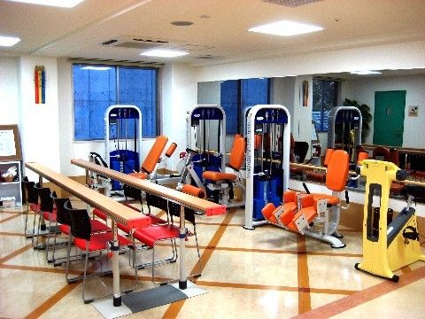 室内には平行棒のほか、さまざまなトレーニング機器が置かれている。壁には窓があり、天井にはエアコン、照明設備が設置されている。