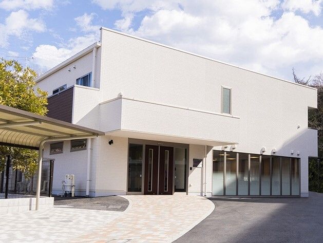青空が広がっている施設の外観パース。２階建ての平たい建物