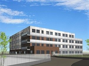 4階建ての建物。白とブラウンでまとめられ、駐車場が付き、緑も植えられている。