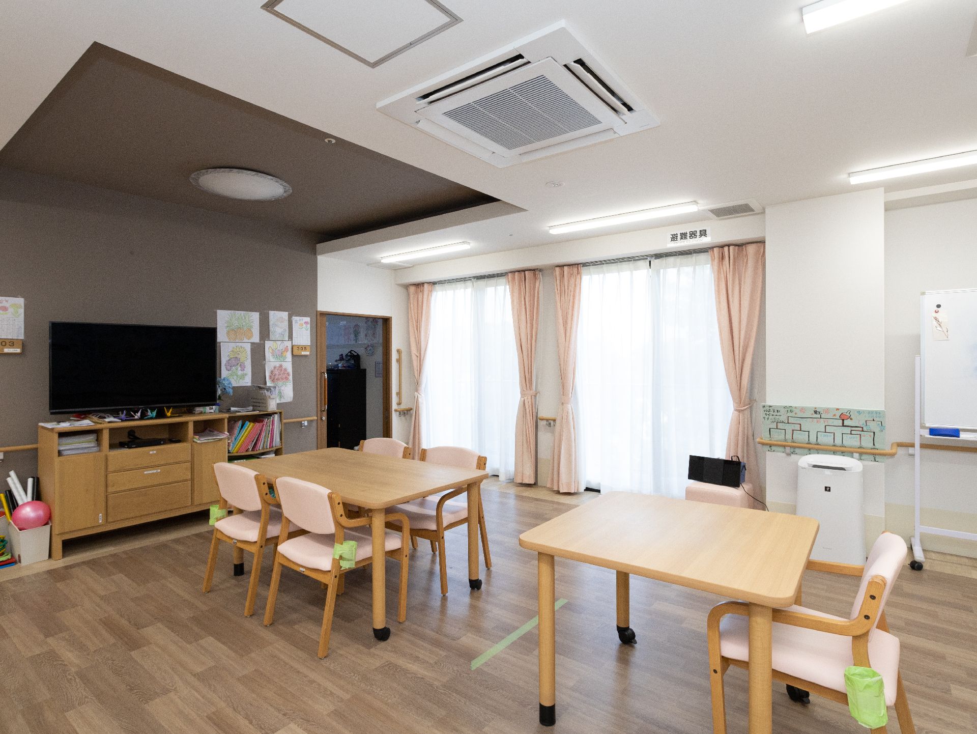 大きなテレビが設置され、テーブル、椅子が並べられているリビング