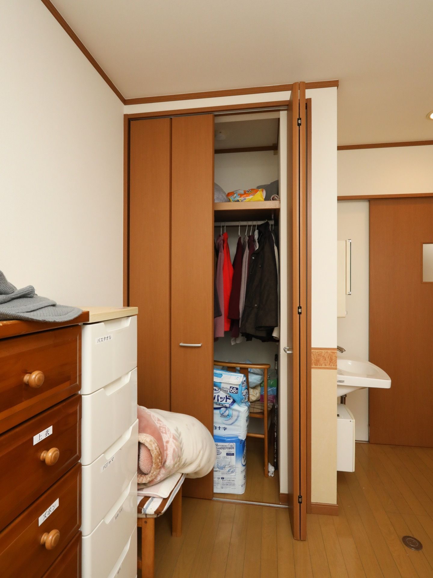 折りたたみ式の両開きの扉が設置された収納クローゼットが備え付けられている。棚やハンガーポールが取り付けらている。