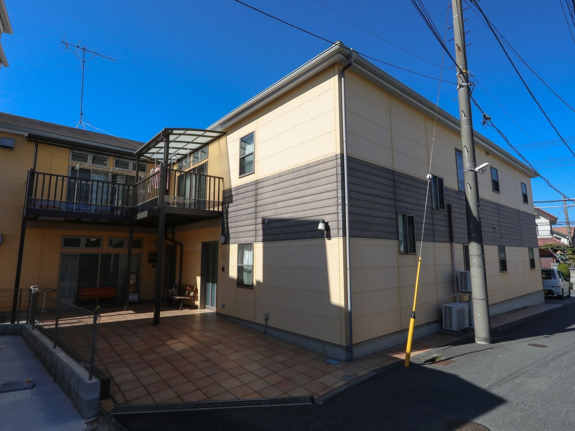 駐車場付きの2階建ての建物。ベージュとブラウンですっきりとした印象。