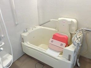 白を基調とした浴室にはシャワーや手すり、介護対応の浴槽が設置されている。