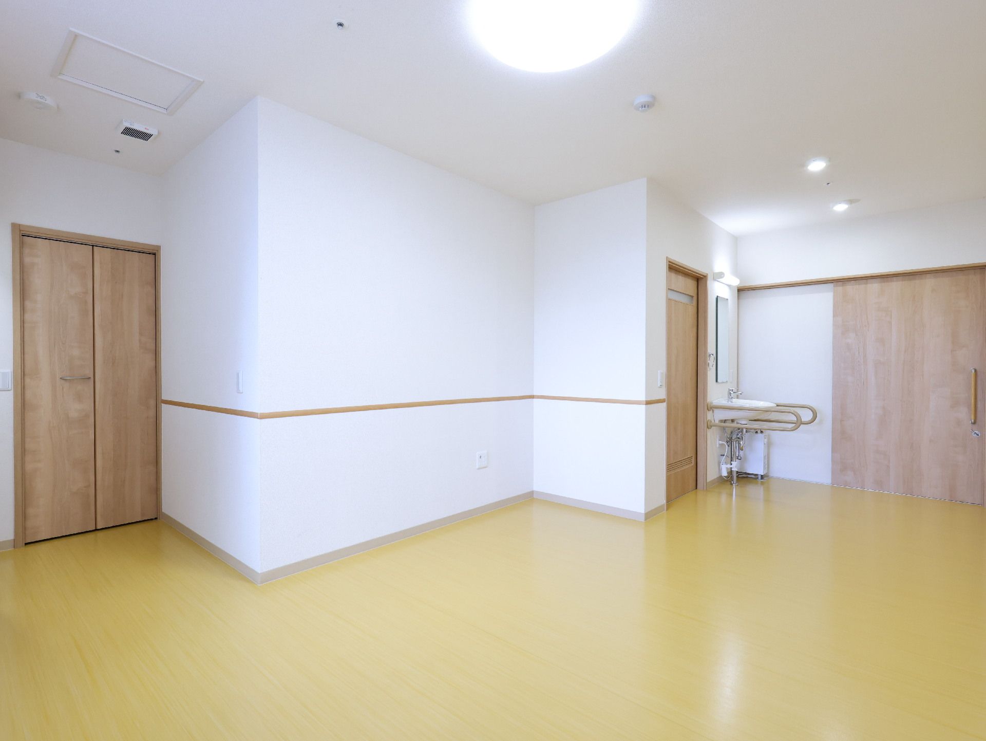 黄色の床に独立洗面台のある廊下