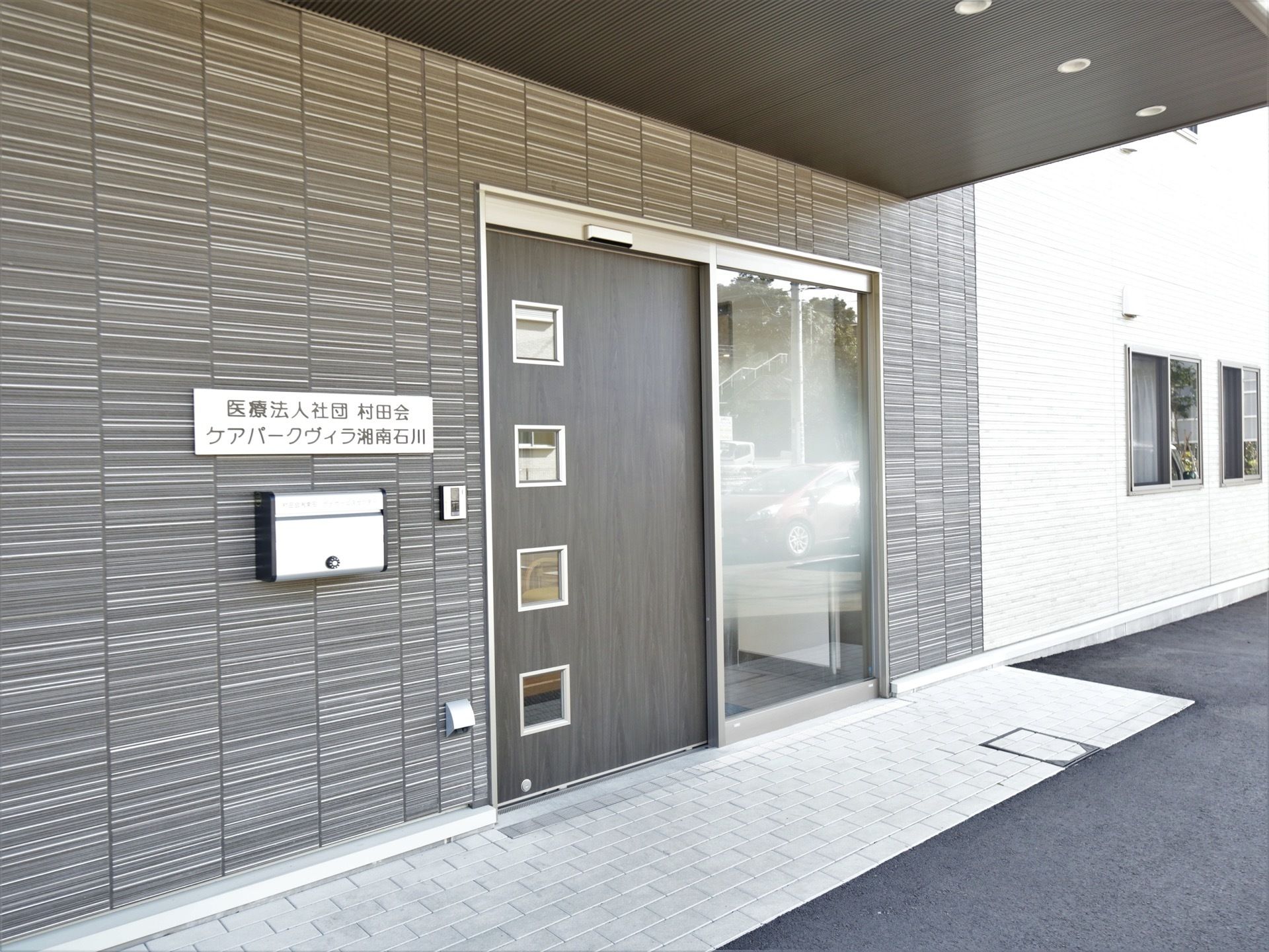 玄関は、上下方向に４枚のスリットが入った大きな自動扉である。玄関の左側に横長の看板が取り付けられている。