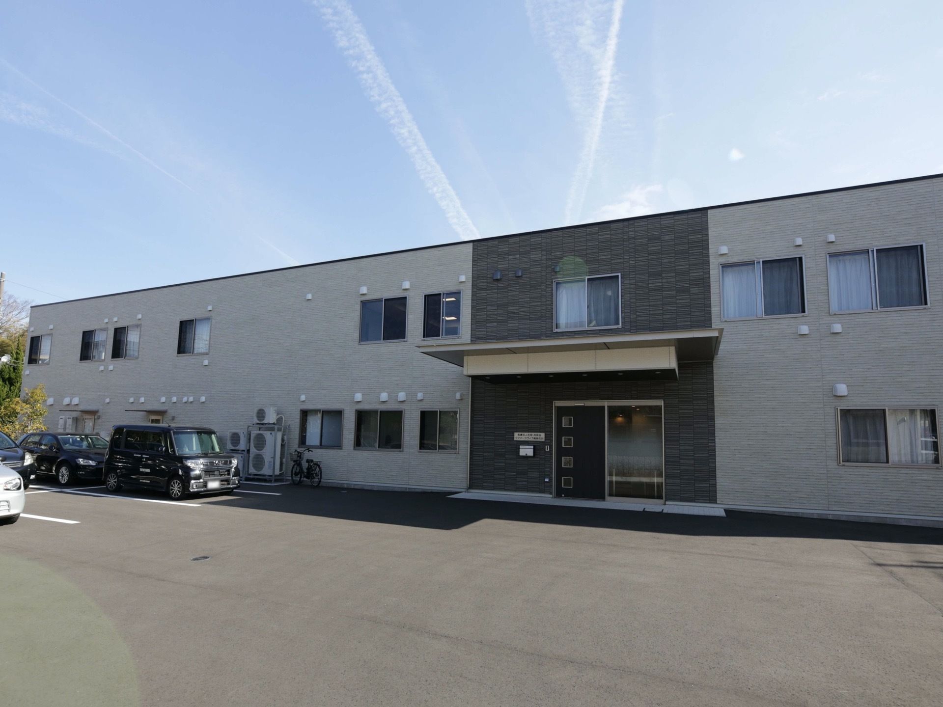 モダンなタイル張りが施された、二階建ての施設である。玄関のすぐ近くに、駐車スペースが完備されている。