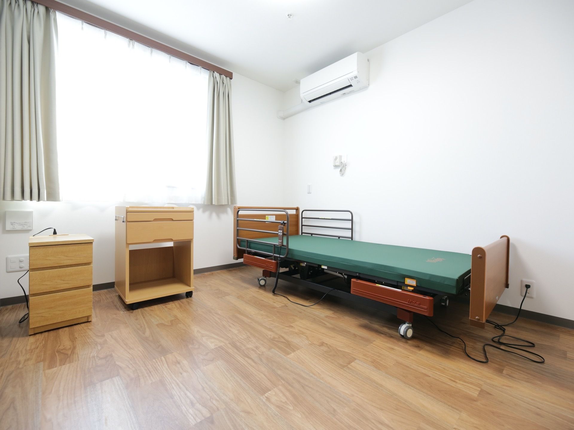 居室はすべて大きな窓のある個室となっている。エアコンと介護用ベッド、収納用のチェストが完備されている。