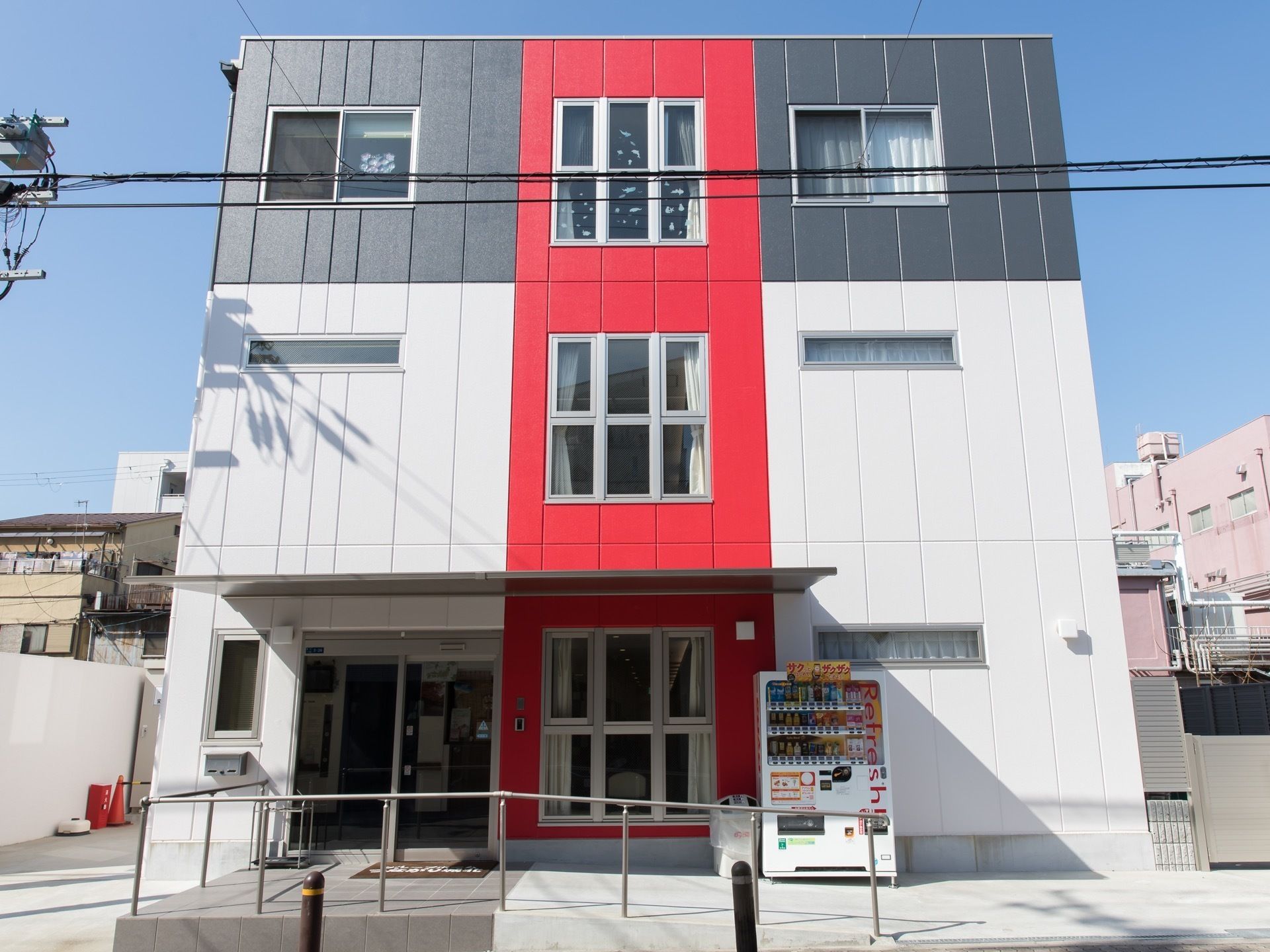 青と白と赤で塗装された３回建ての建物である。入り口まではスロープになっていて、手すりも取り付けられている。