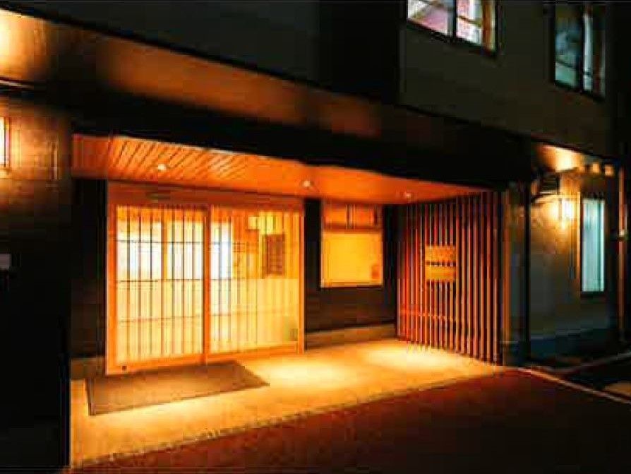 明かりが灯った玄関。和の雰囲気が漂っていて、玄関ドアは格子戸になっている。