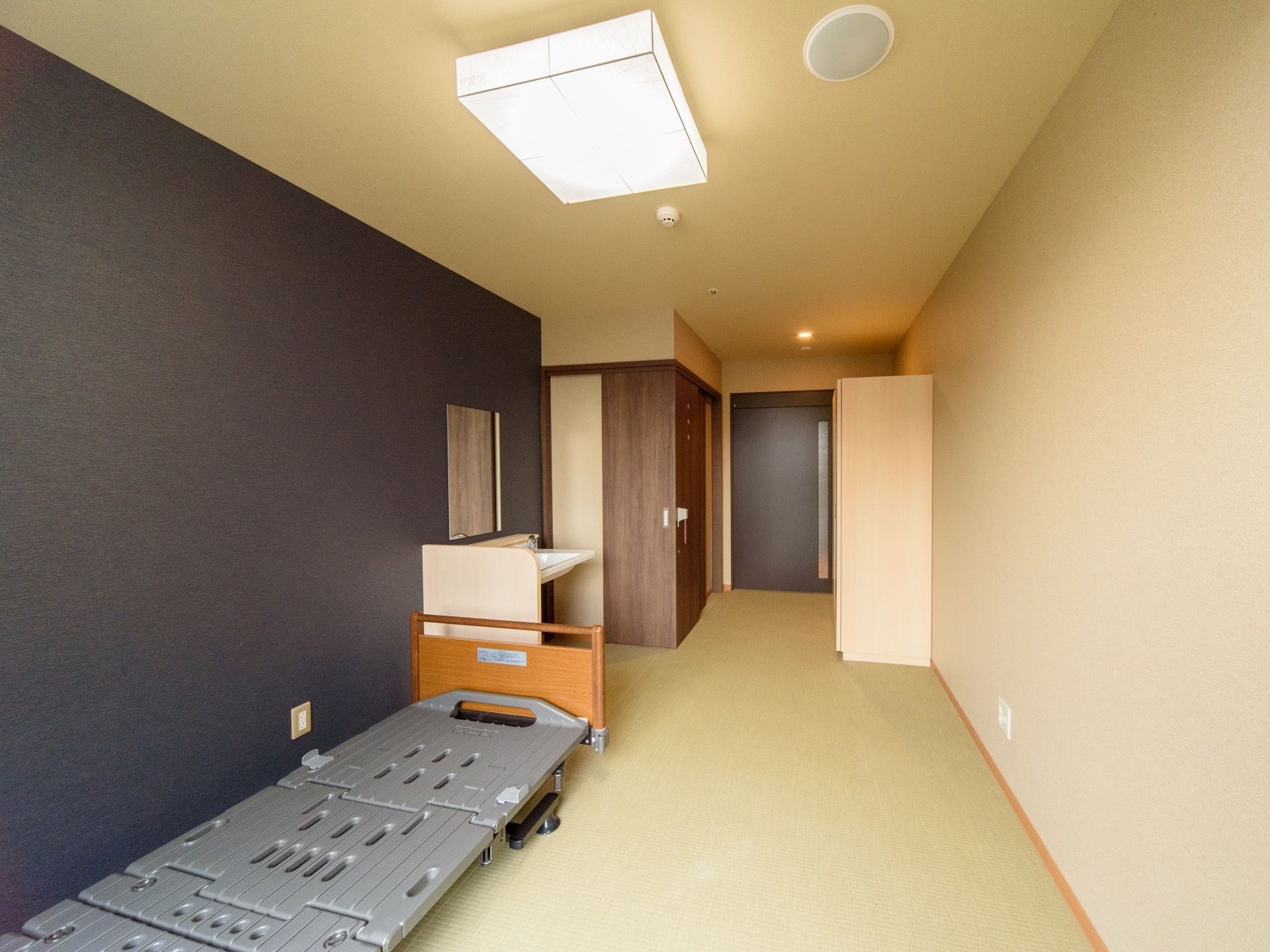 ２色の壁紙で構成された居室である。壁際には、ベッドが１台置かれ、壁に鏡が取り付けられた洗面台も設置されている。
