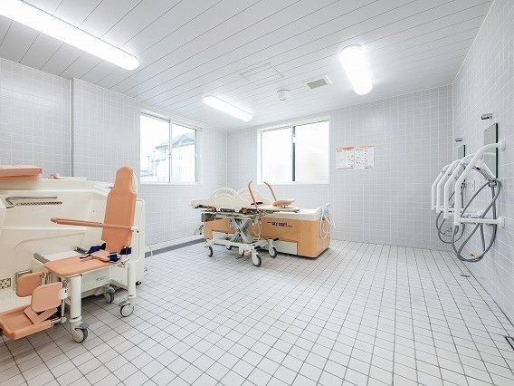 車いす対応と寝たまま入浴可能な機械浴が完備され、介護度が高い人にも対応しているタイル張りの浴室。