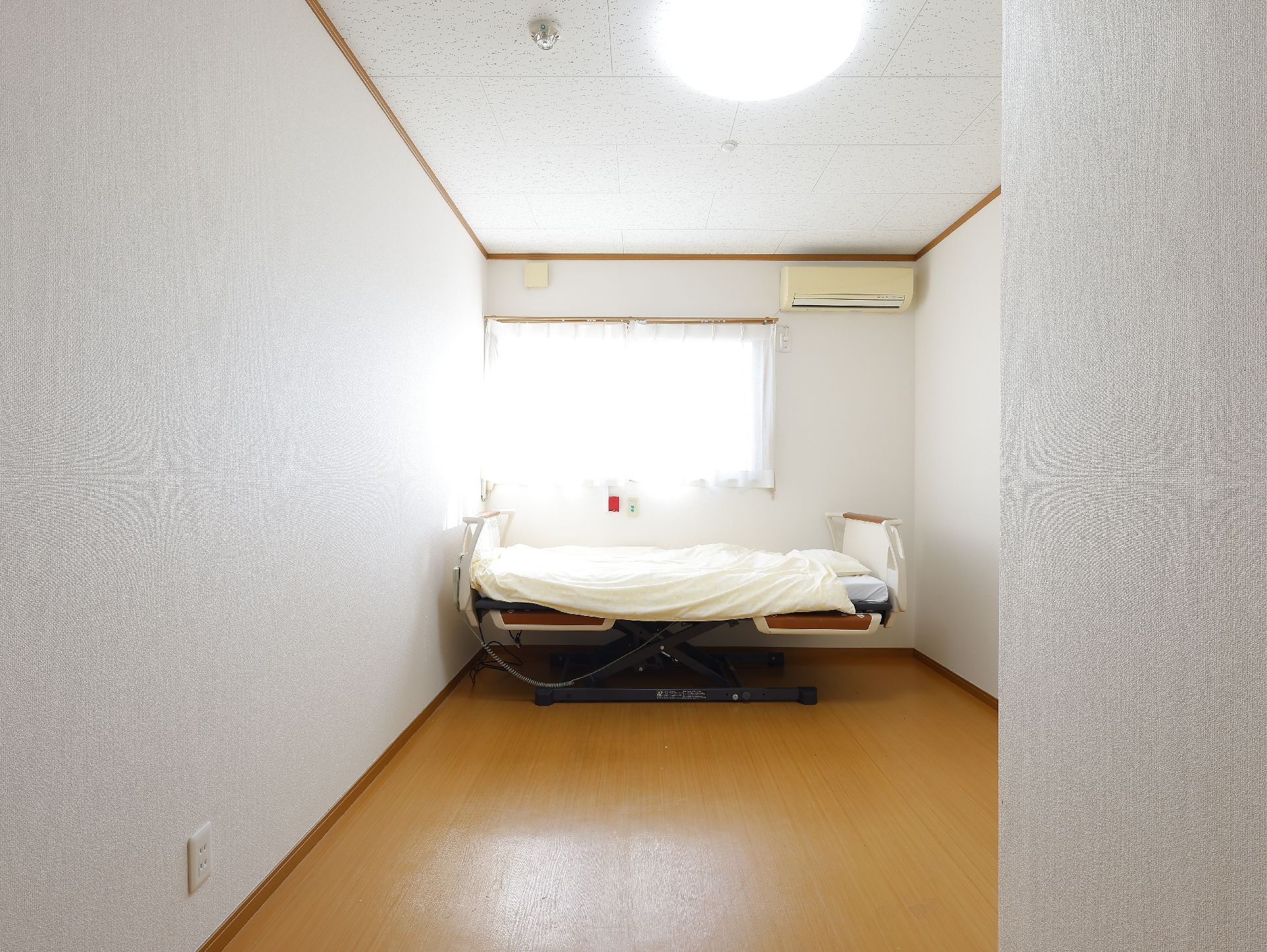 窓から日差しが差し込み、介護ベッドが置かれている居室