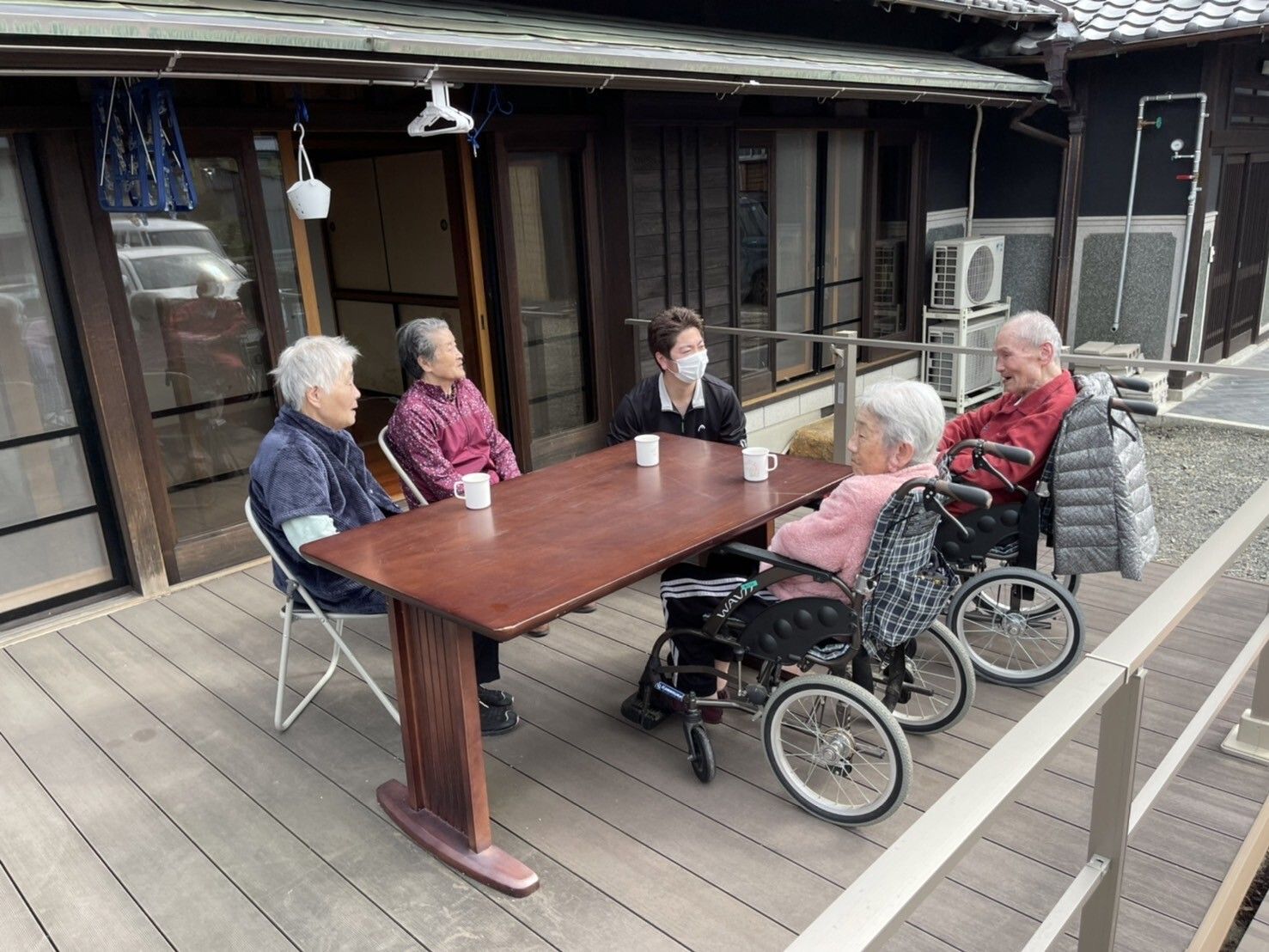 黄色い手すりに掴まる高齢男性を介助するヘルパー