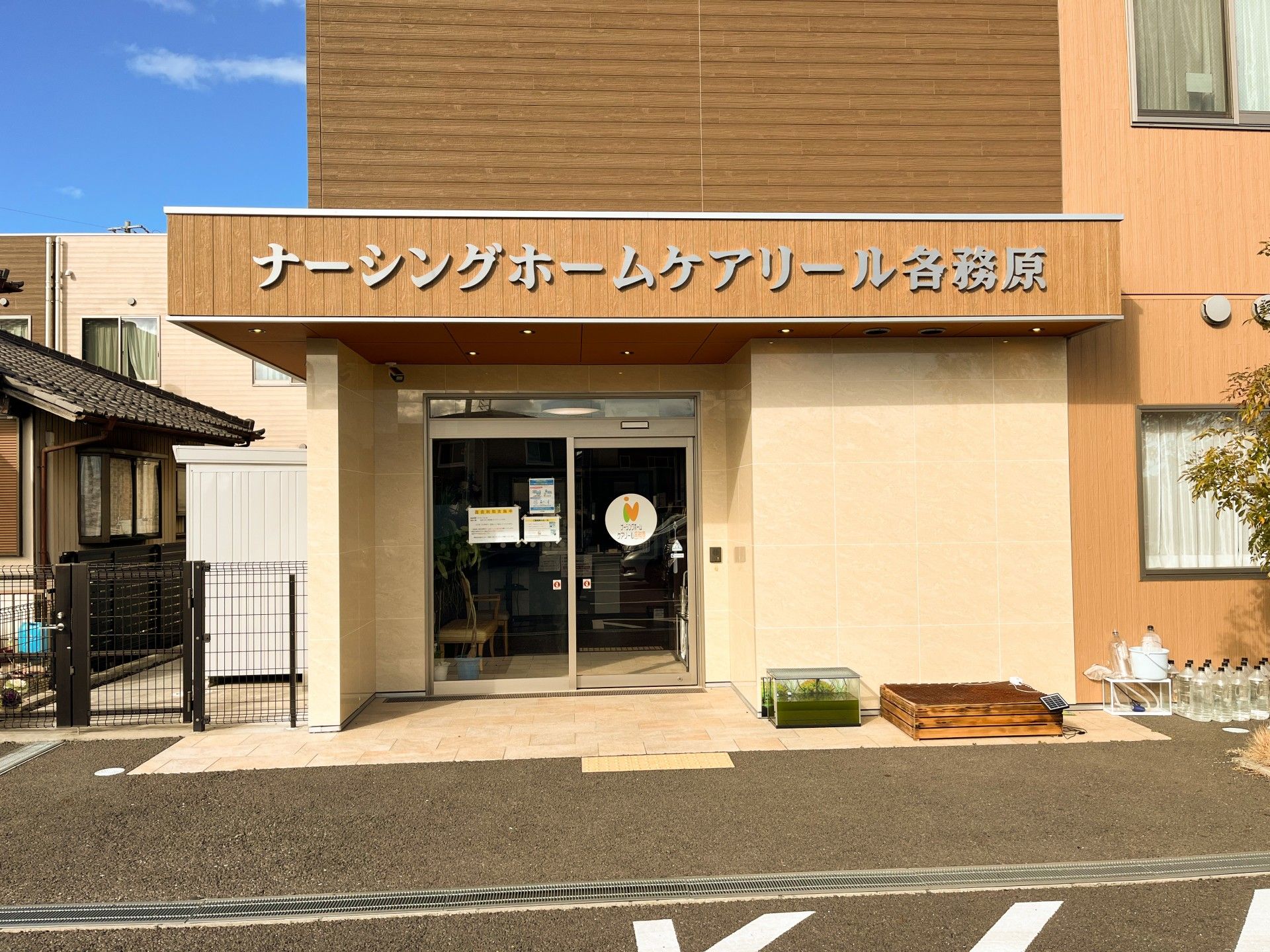 寝ている高齢者の女性に笑顔で話しかけている女性スタッフは花柄のエプロンを付けている。