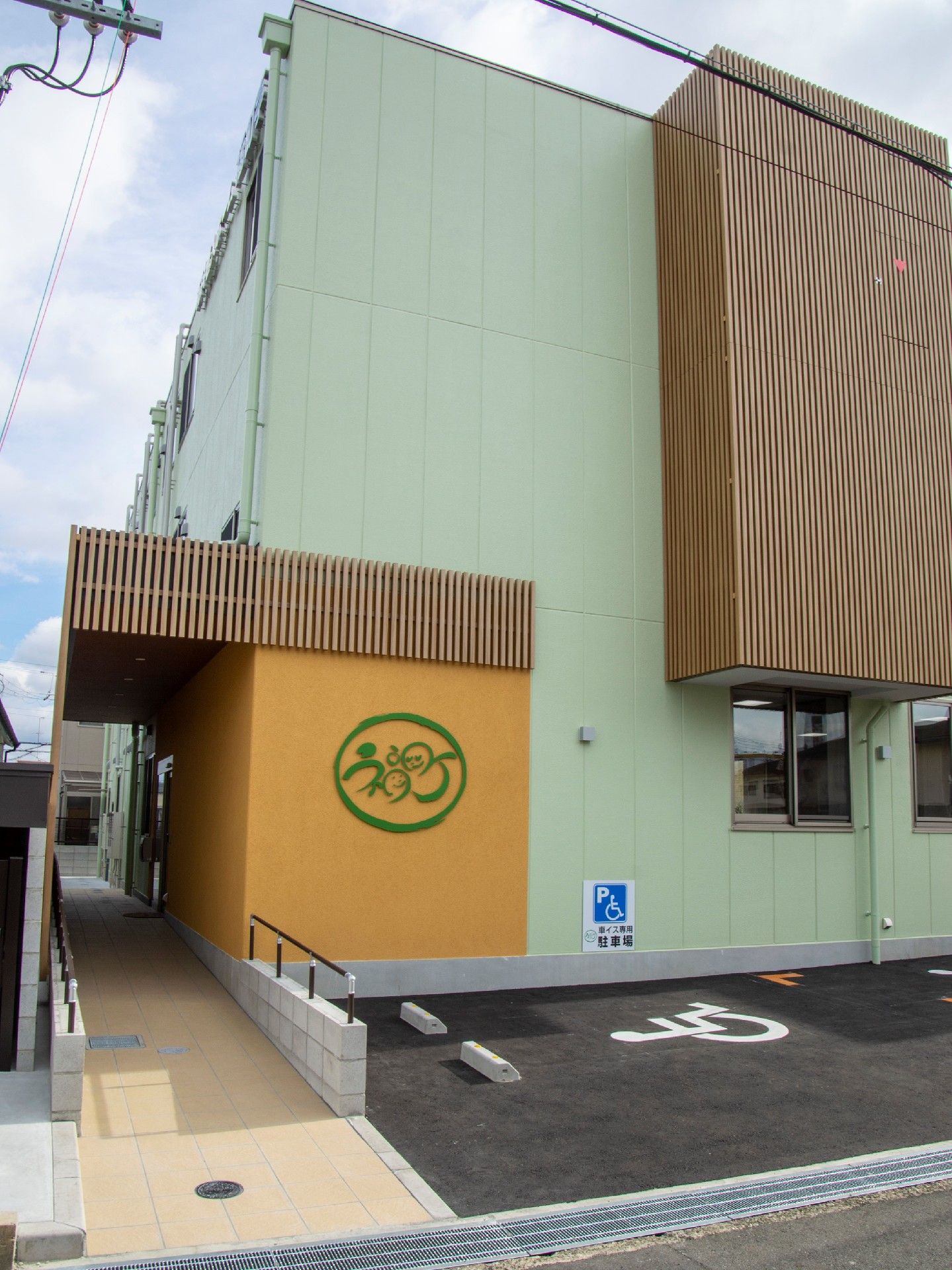 手前に駐車場がある建物の外観。木の雰囲気のあしらいが印象的な建物
