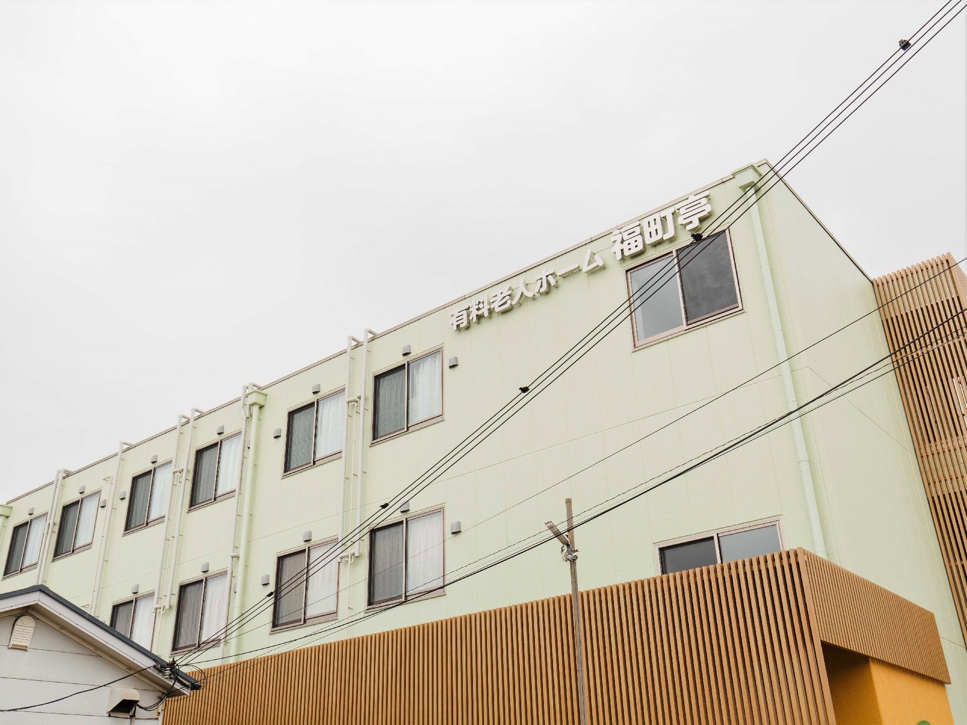 白い壁の鉄骨造の建物の上の部分。外観を下から見上げるように写したもの