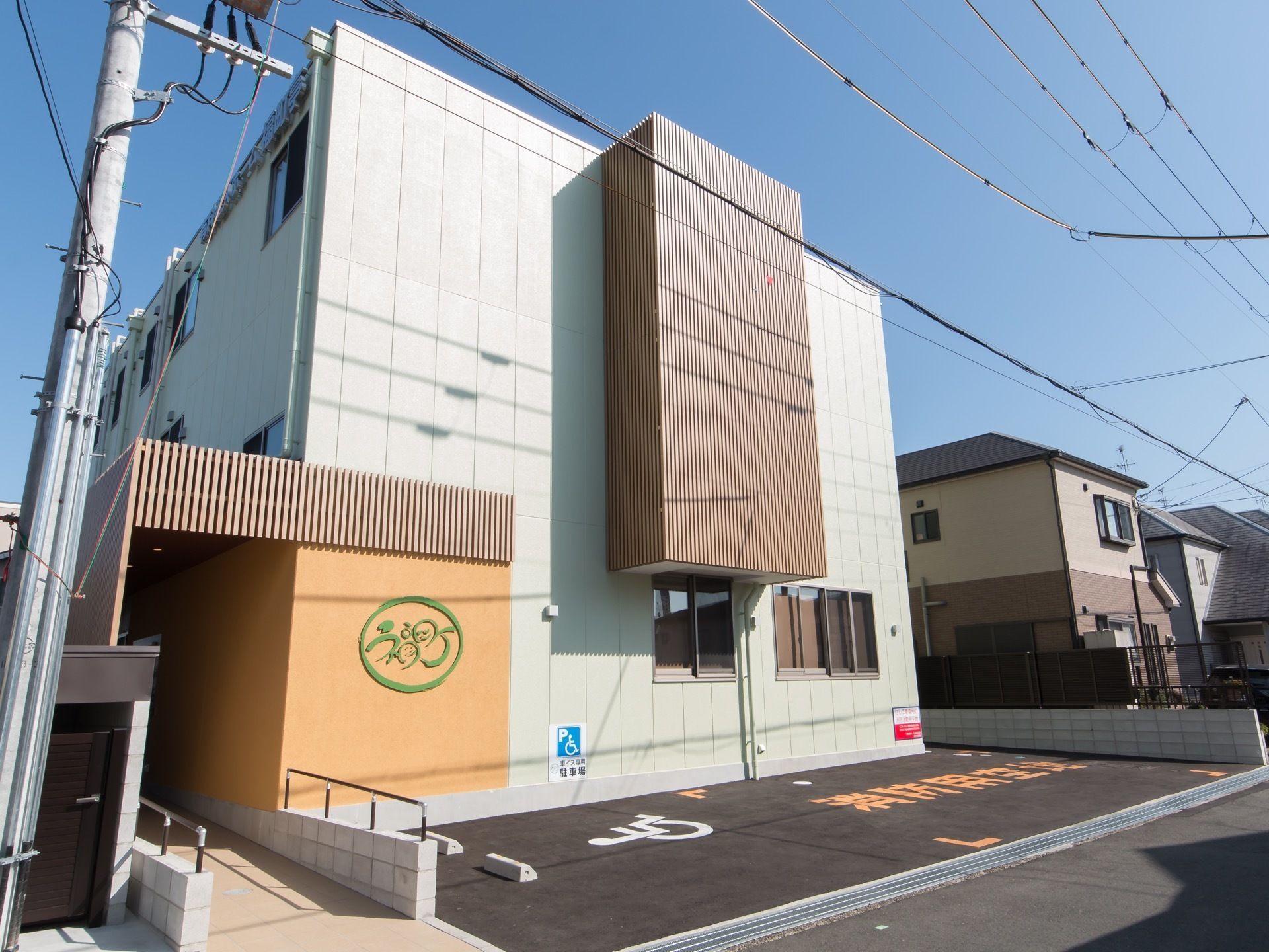 施設外観はホテルのようにスッキリとデザインされている。エントランスに続くスロープがあり、建物前には車椅子用の駐車スペースと消防用空地がある。