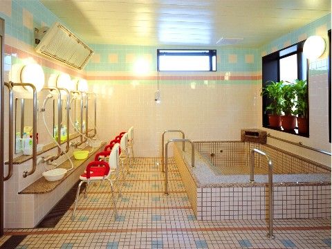 窓側の壁面沿いに四角い大浴槽、向かい側の壁面に洗髪コーナーが多数並んでいる大浴室
