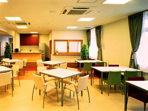 食堂には大きな窓があり、天井にはエアコン、照明設備が設置されている。床の上にはテーブルセットが並べられている。