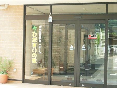 大きくホーム名が書かれた玄関ドア。自動ドアでAED設置のステッカーも貼られている。