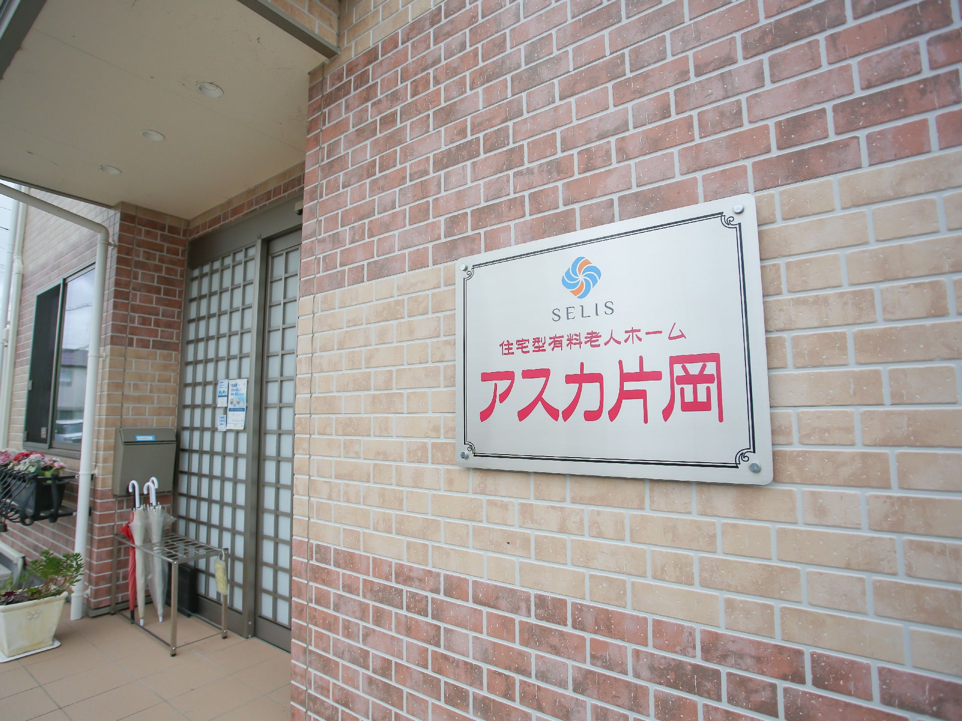 車いすにのる男性とそれを押している女性スタッフ。両側に自然が広がる遊歩道の写真