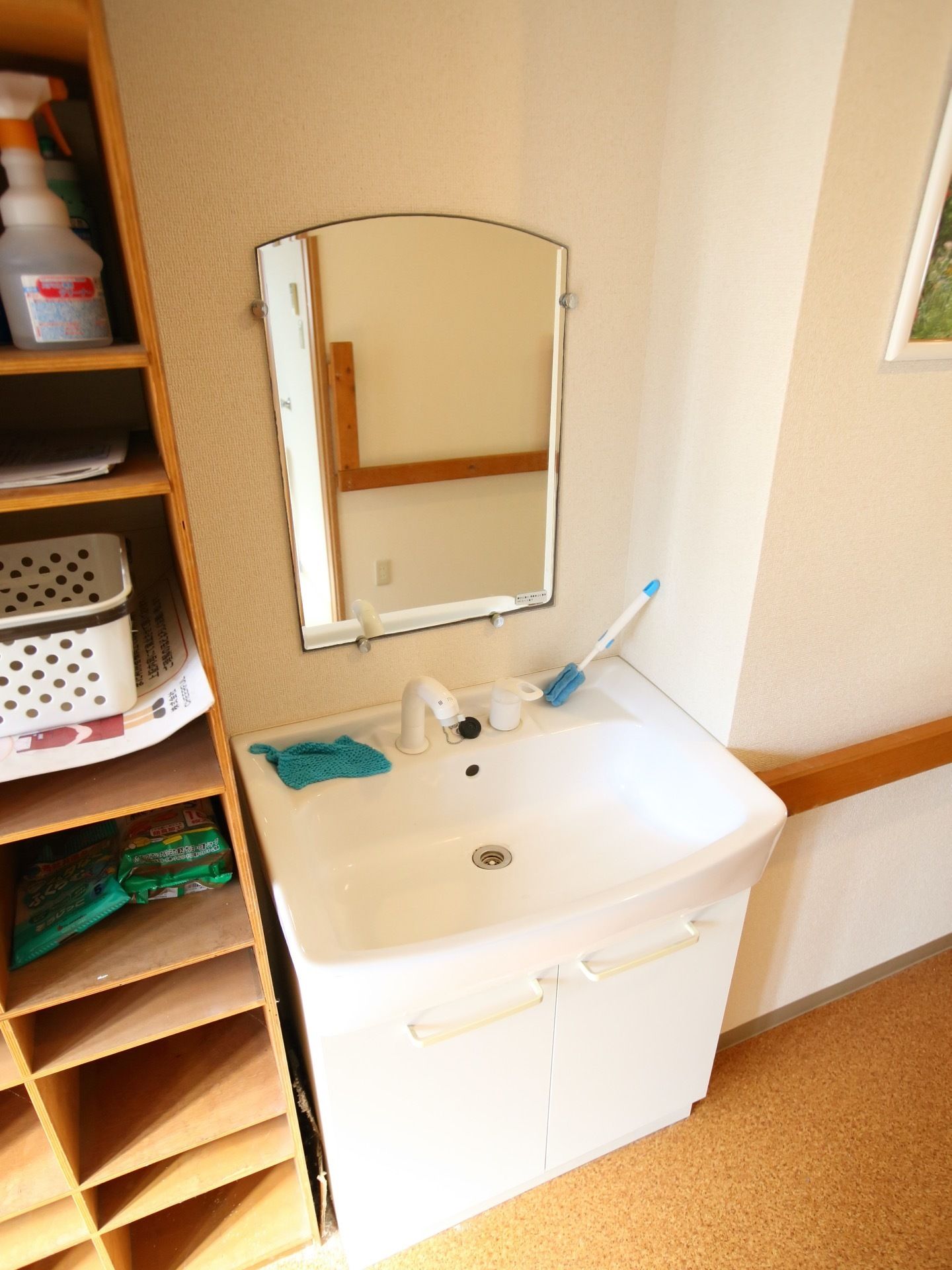 鏡付きの洗面台が通路に設置されている。物が少なく、整然としている。低めの洗面台で、車椅子のままでも使用できる。
