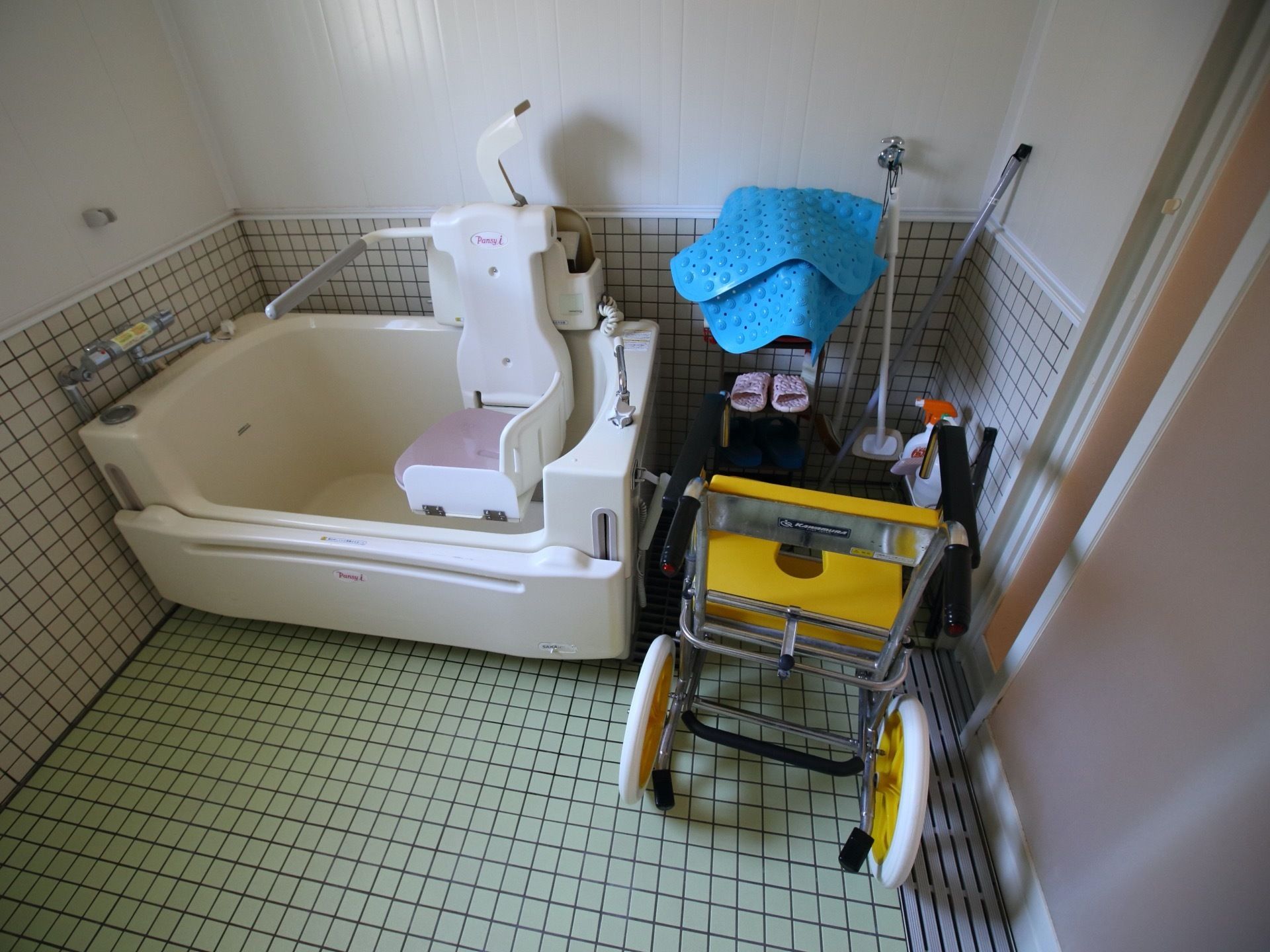 段差のない広々とした浴室である。清掃が行き届いている。浴室の隅には、滑り止めマットや清掃用具が整頓されている。