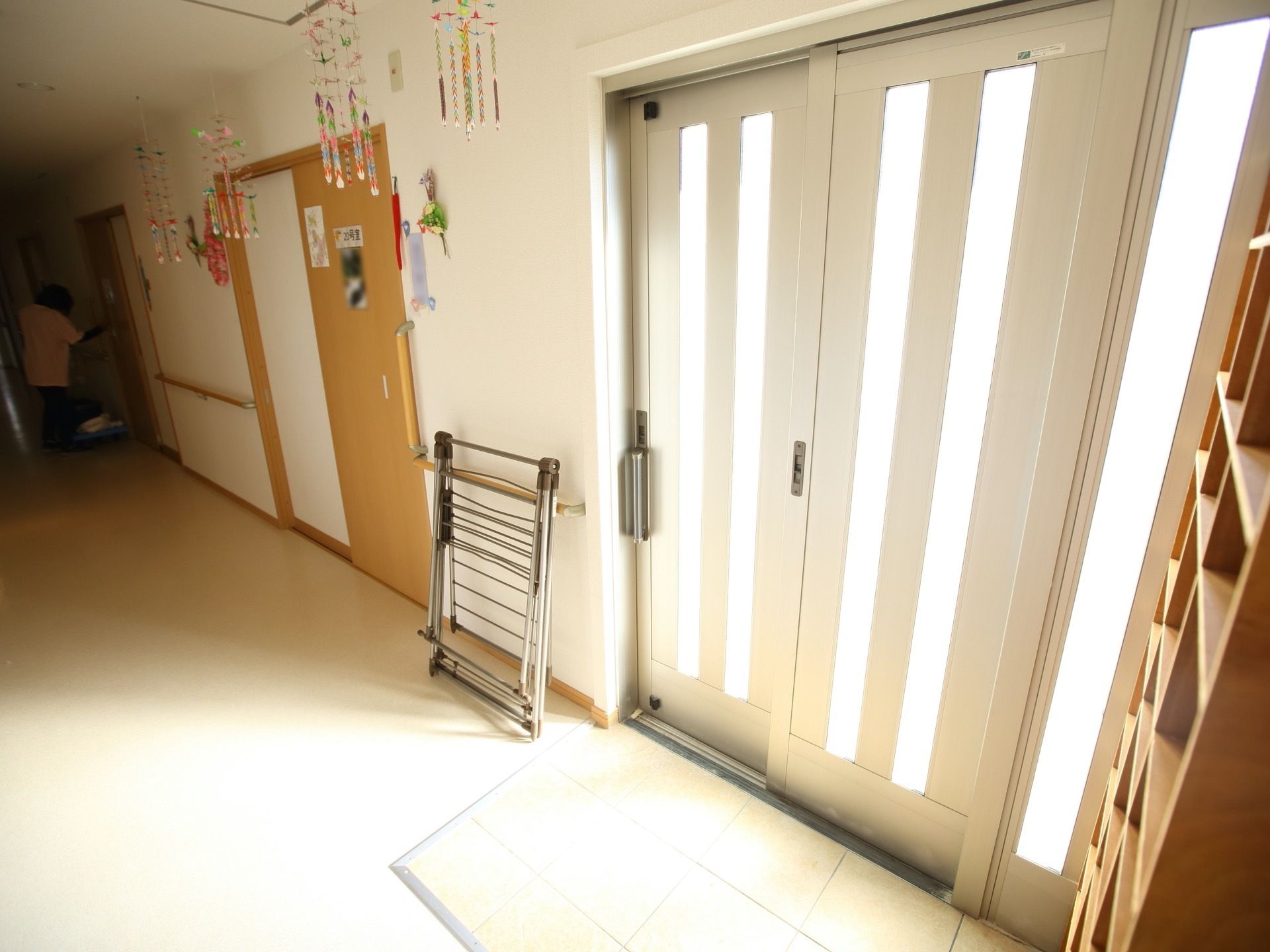 玄関扉は3枚の引き戸が使われている。スリットがあり、外からの光が多く差し込んでいる。バリアフリーになっている。