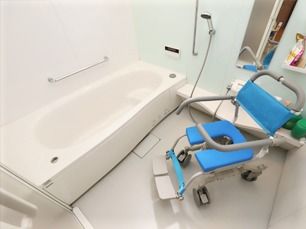 手すりがたくさんついた浴室には一人用の浴槽があり、シャワーや浴室用車いすも付いている。