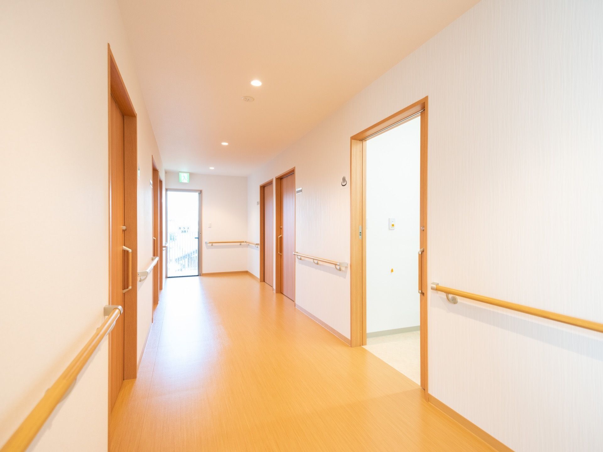 廊下の床や建具、手すりは全て明るい木調でまとめられており、シンプルで清潔な印象を与える。ドア以外の壁には手すりが設置されている。