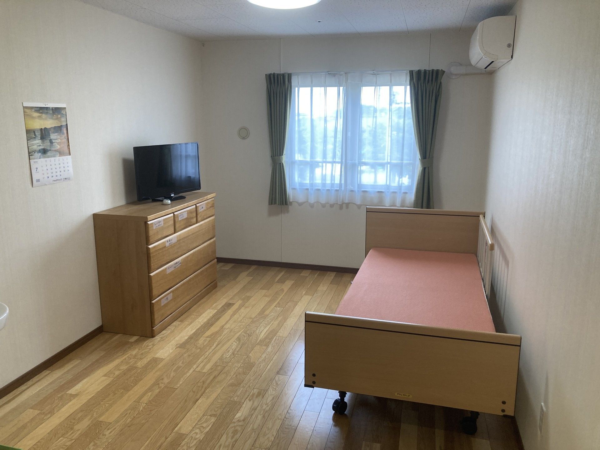 なにかを見て笑顔で手をたたいている高齢女性とスタッフの様子。施設での一場面の写真