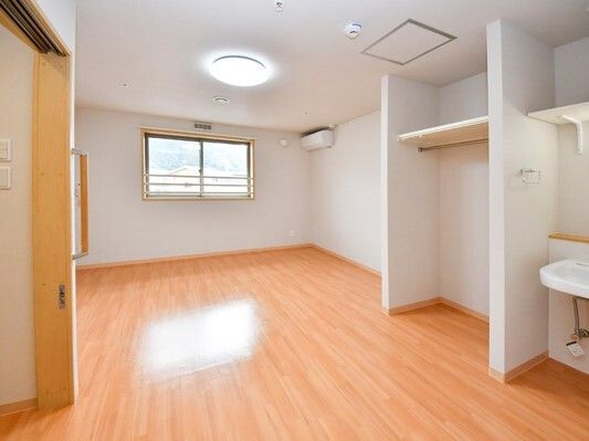 大きな窓にはカーテンはなく、広いフローリングの部屋には大きなオープンタイプの収納と車いす対応の洗面所がある。
