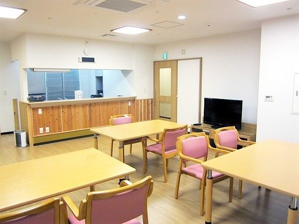 木製のダイニングテーブルが並び、テレビが置かれたリビングダイニングにはキッチンもある。