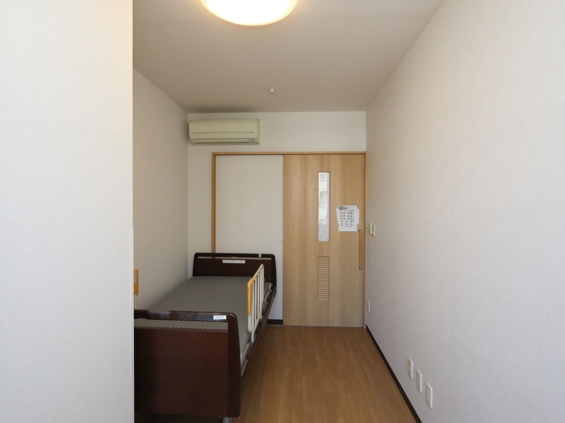 居室はフローリング仕様の床で、エアコンとベッドが設置されている。扉は横に引いて開閉でき、スムーズな移動が実現される。