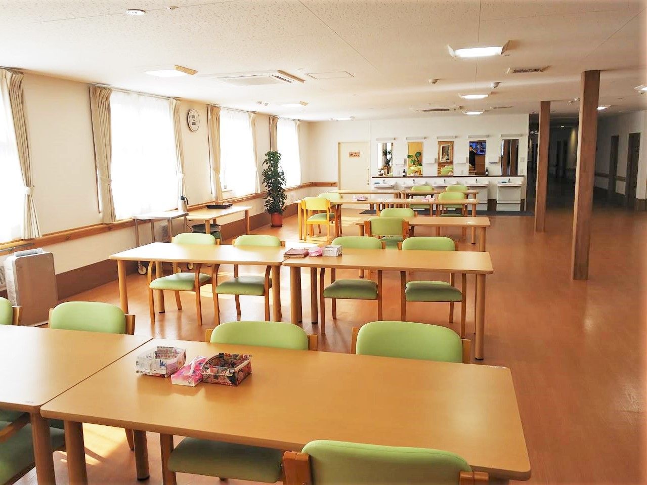 屋外で車いすに乗って散歩を楽しむ男性入居者とエプロン姿の女性スタッフ。