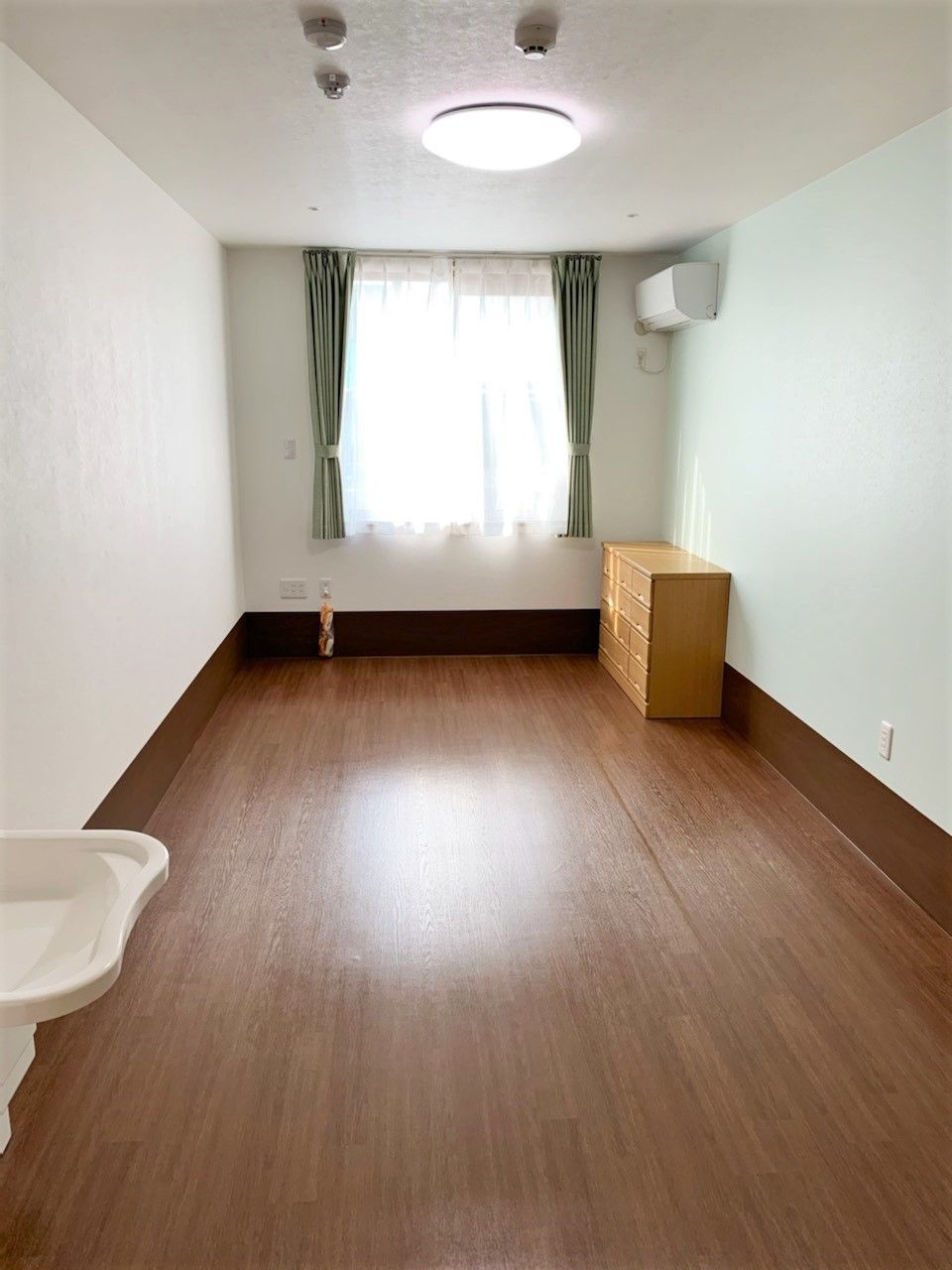 洗面所付きの居室はシンプルで白を基調としたデザイン。大きな窓もある。