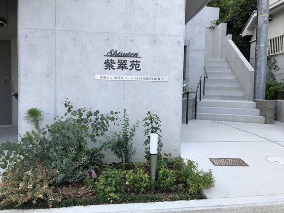 コンクリート打ち放しの施設の外観。看板があるエントランス付近