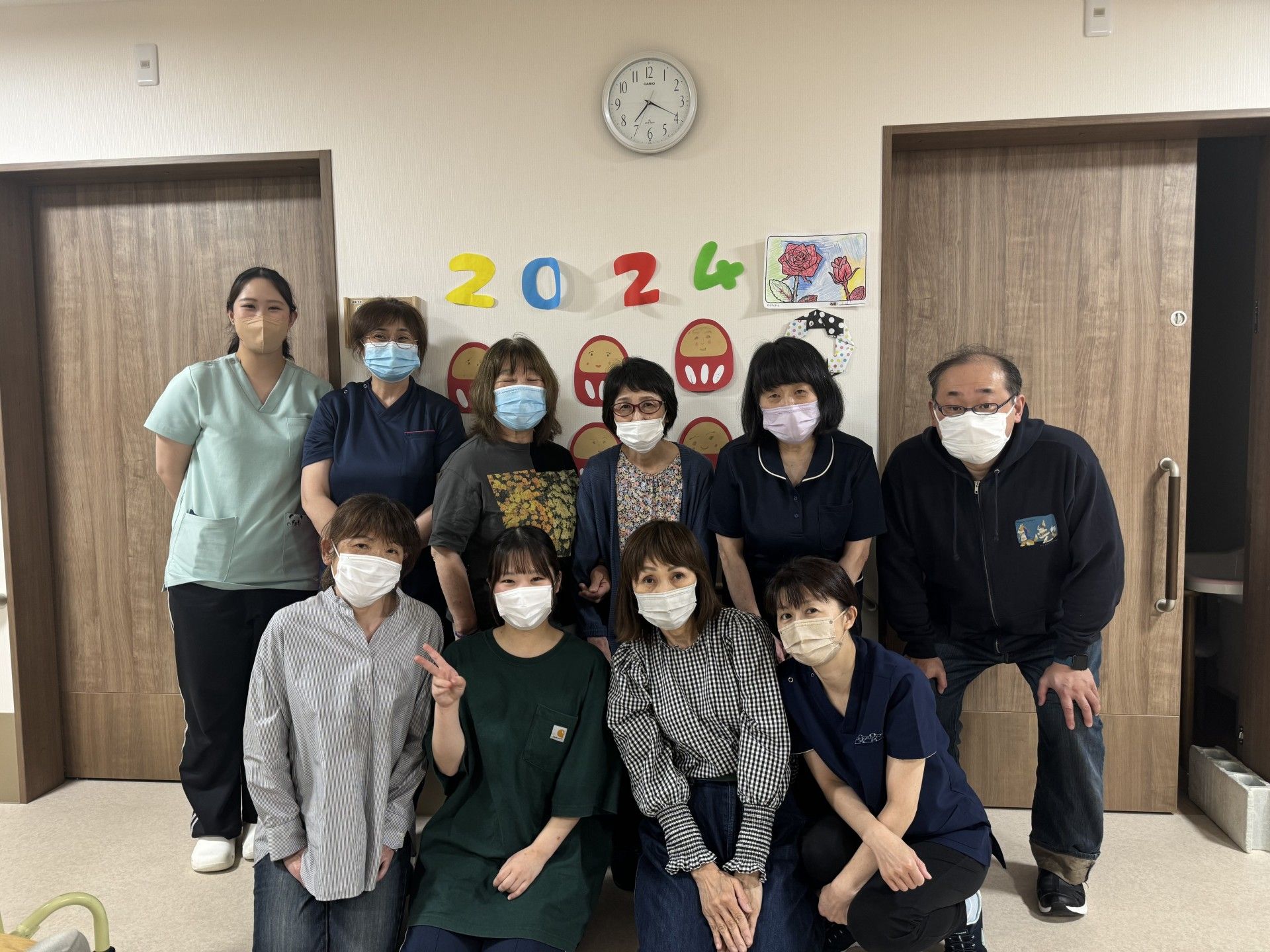自然豊かな場所を車いすで散歩している高齢男性とそれを補助しながら話している女性スタッフ