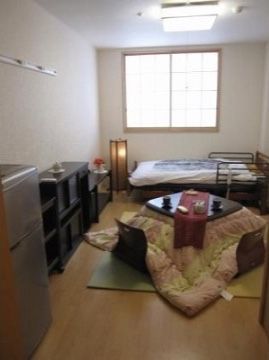 障子の窓やこたつが用意された、落ち着くことのできる空間である。陽の光がさしこみ、生活のしやすいシンプルな部屋となっている。