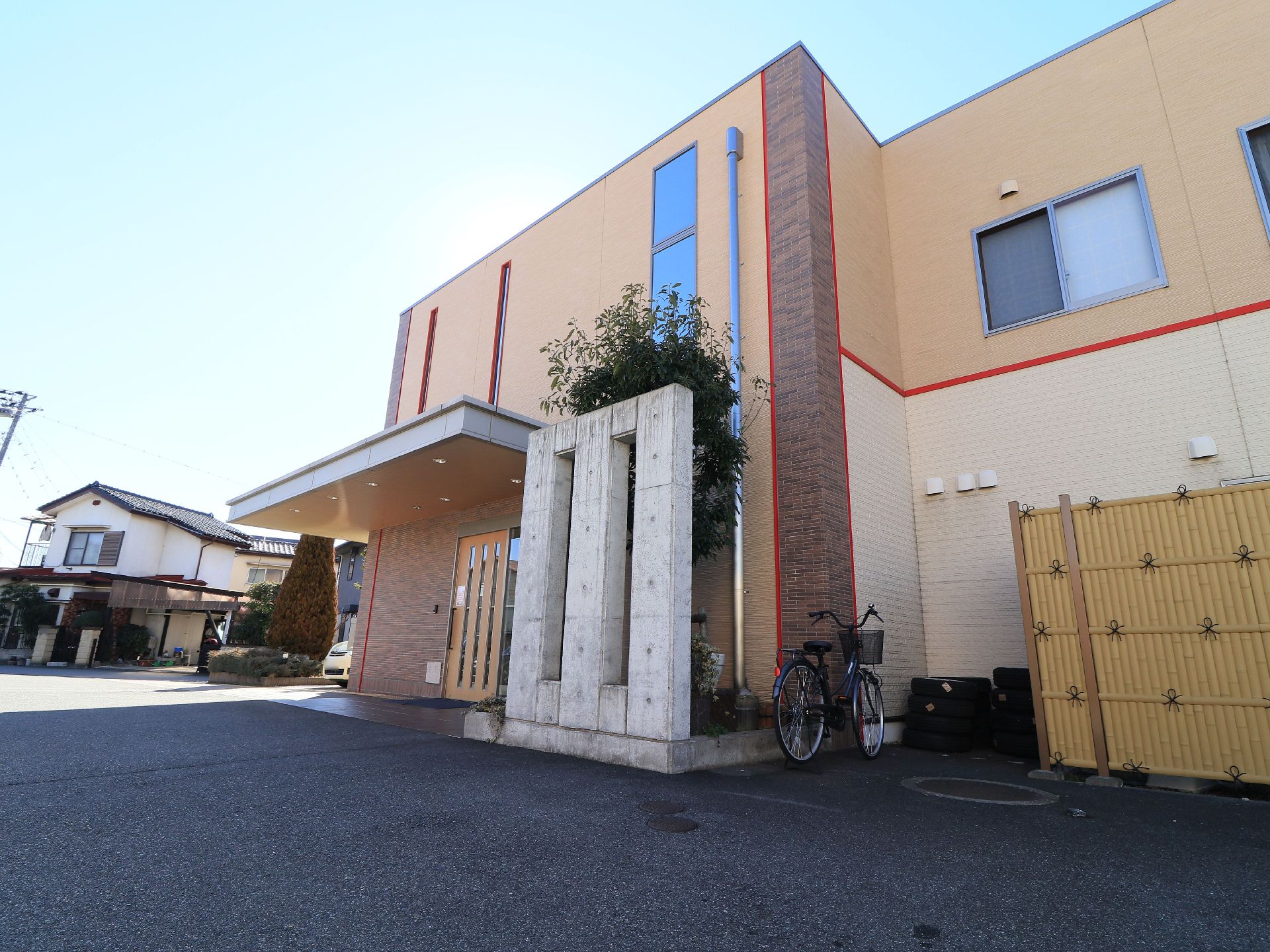 施設は、ライトブラウンベースに赤のラインがオシャレな２階建ての建物である。竹垣で作った柵があり、スッキリとした外観になっている。