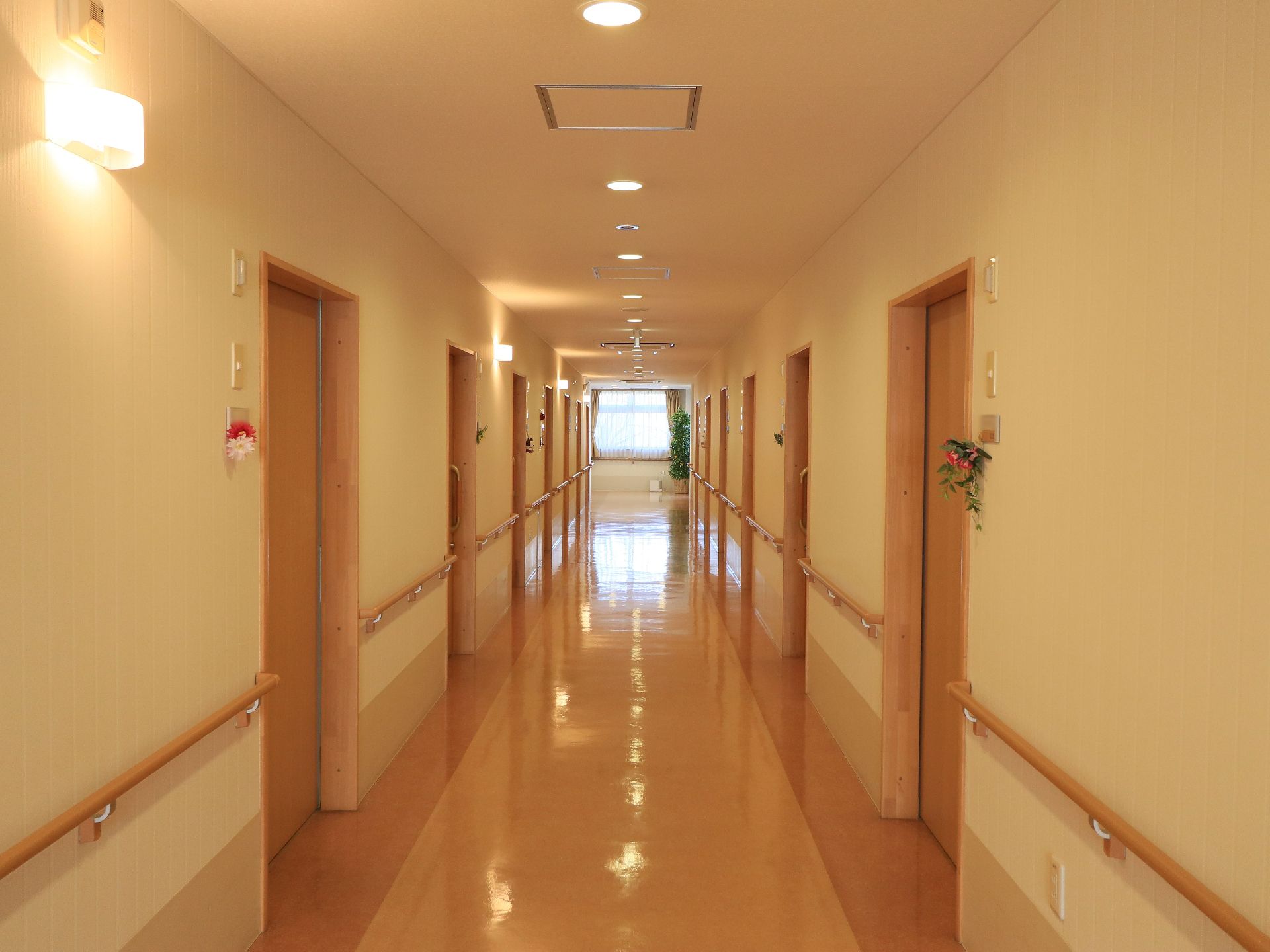 あたたかみのある雰囲気の廊下は、幅が広く、壁には手すりが設置されている。各居室の入り口には、花が飾られている。