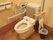 トイレには、温水洗浄便座が設置され、可動式の手すりが取りつけられている。衛生用品の入ったボックスと、ゴミ箱がある。